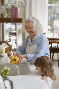 Grandmother washing vegetables in the kitchen